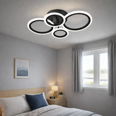 Lustra LED neagra patru cercuri 60W cu telecomanda, montata in dormitor modern, lumina ajustabila 3000-6500K pentru ambient confortabil