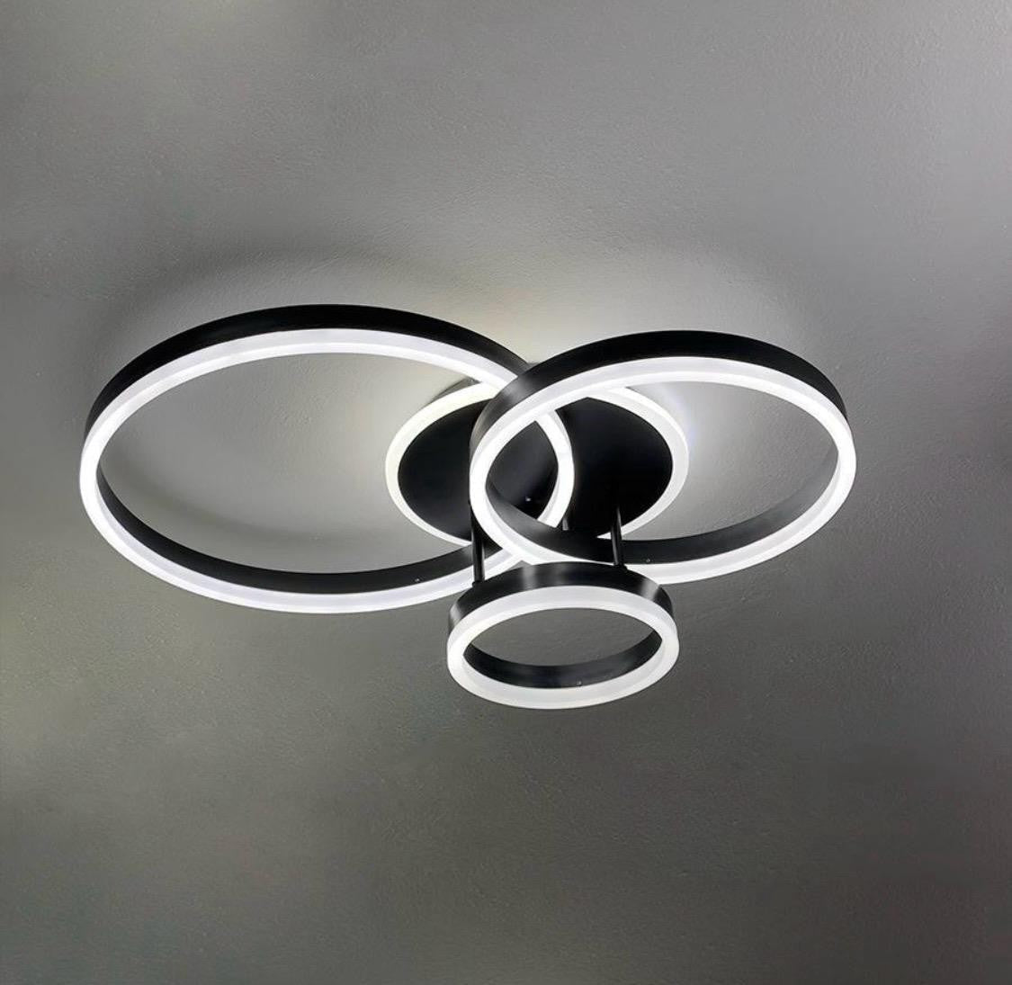 Lustra LED cu 3 cercuri negre si telecomanda, montata in birou modern, oferind luminare clara pentru lucru si un stil decorativ elegant.
