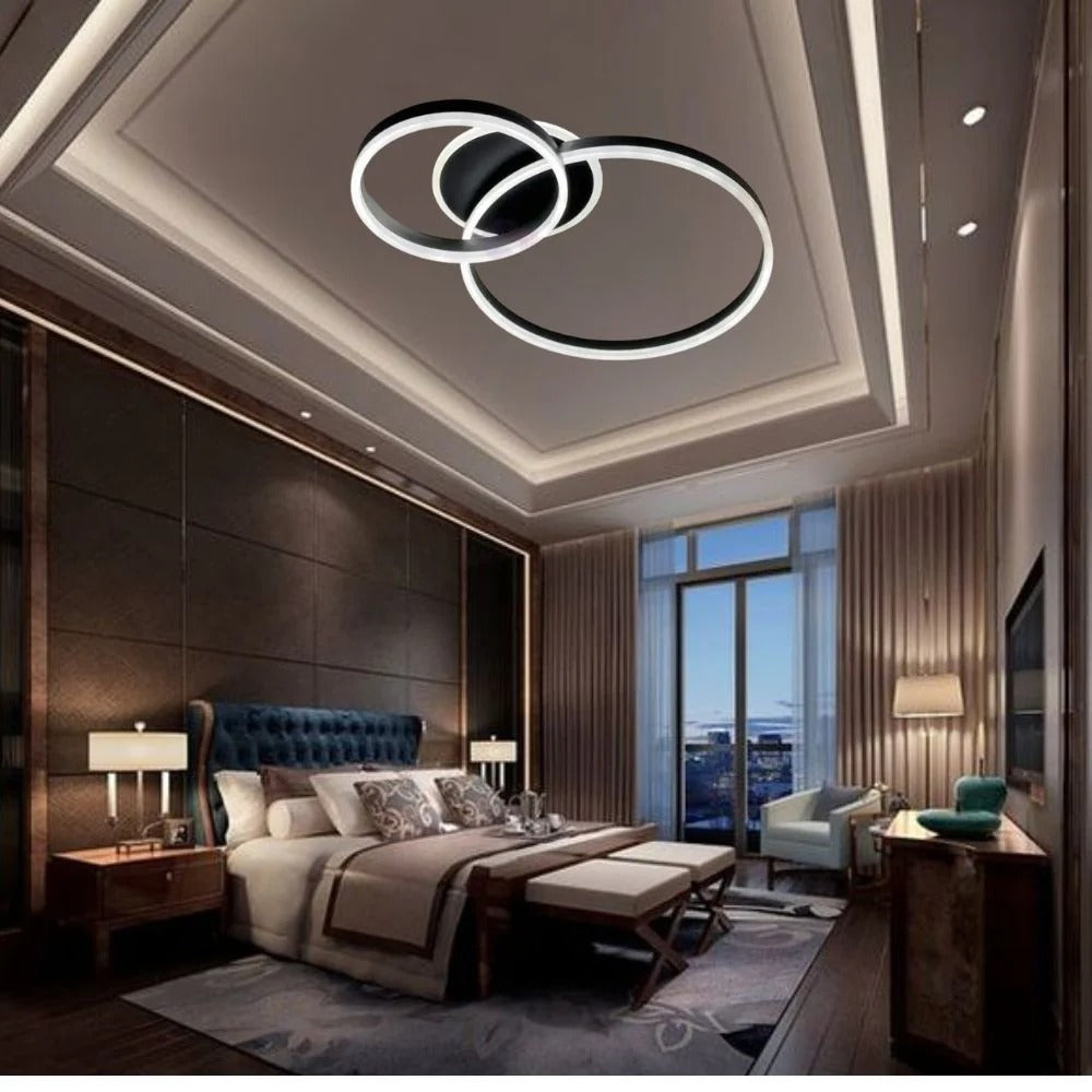 Lustra LED cu doua cercuri negre si telecomanda, montata in dormitor modern, oferind luminare uniforma si o atmosfera eleganta.
